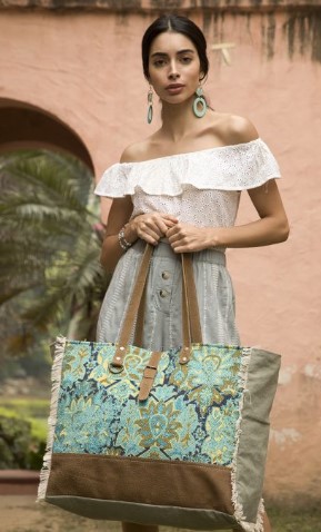 A Woman in White Dress Standing with Aqua Magic Weekender Bag
